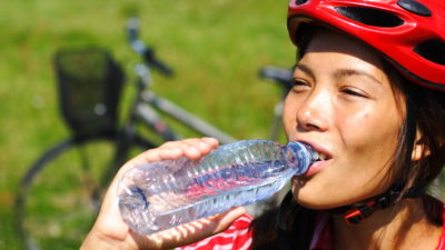 Woman bicyclist drinking from a water bottle